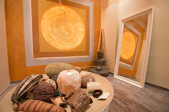Warm gestalteter Wellnessbereich mit Naturdekoration und beleuchtetem Wandbild